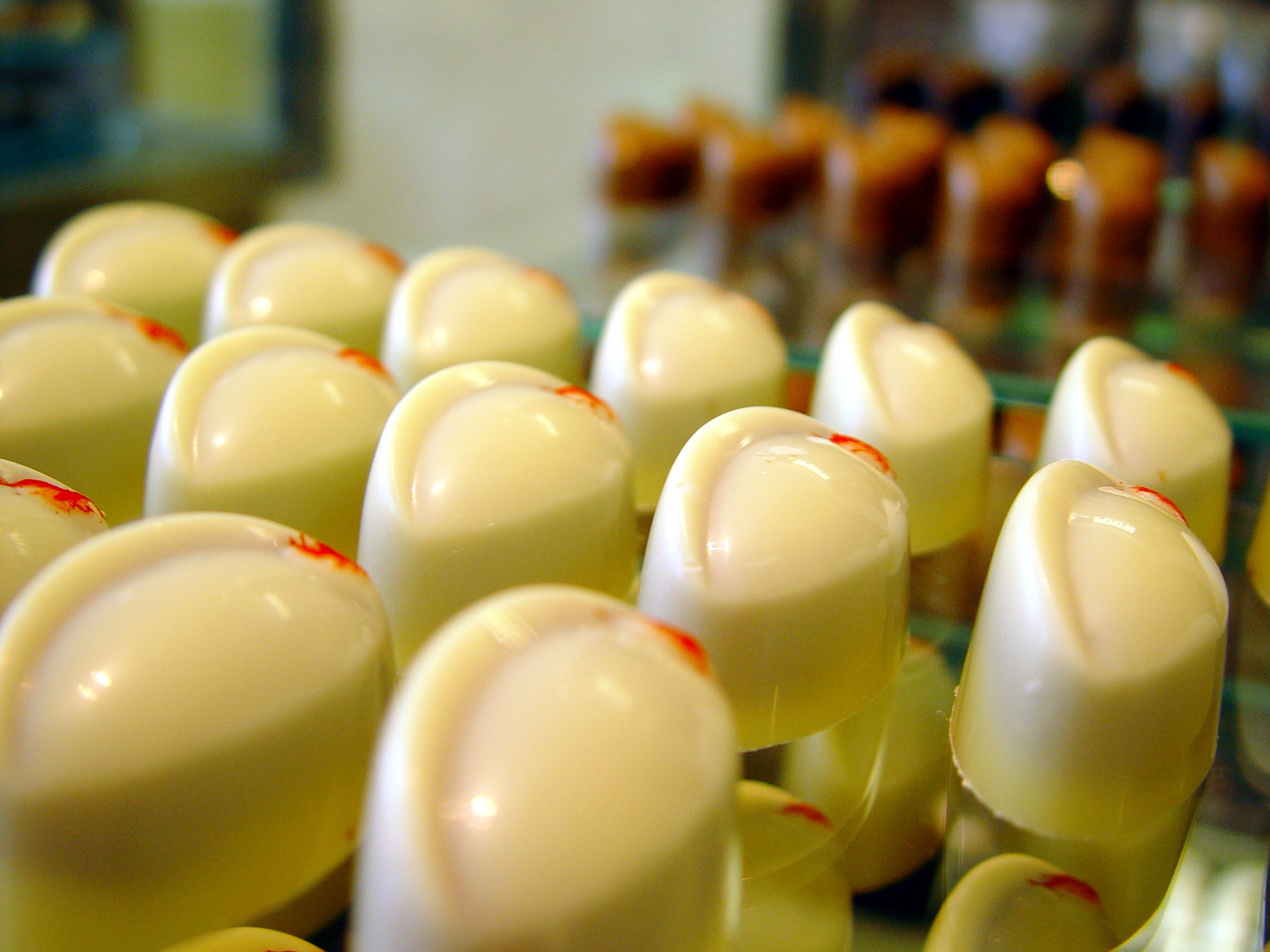 Rijen handgemaakte bonbons met een witte chocoladelaag in de vitrine van PUUR