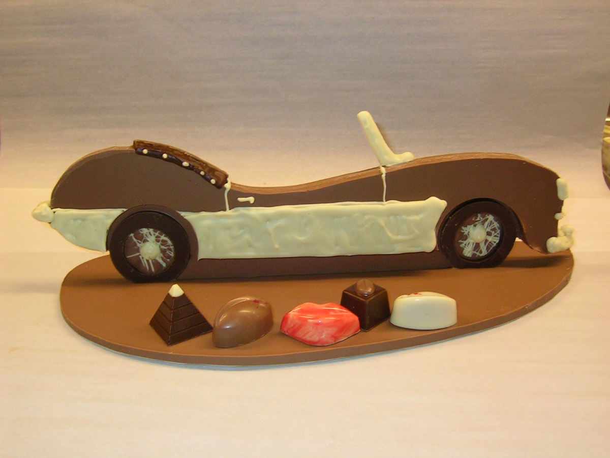 Klassieke auto van chocolade op een ovale plaat, met bonbons ernaast